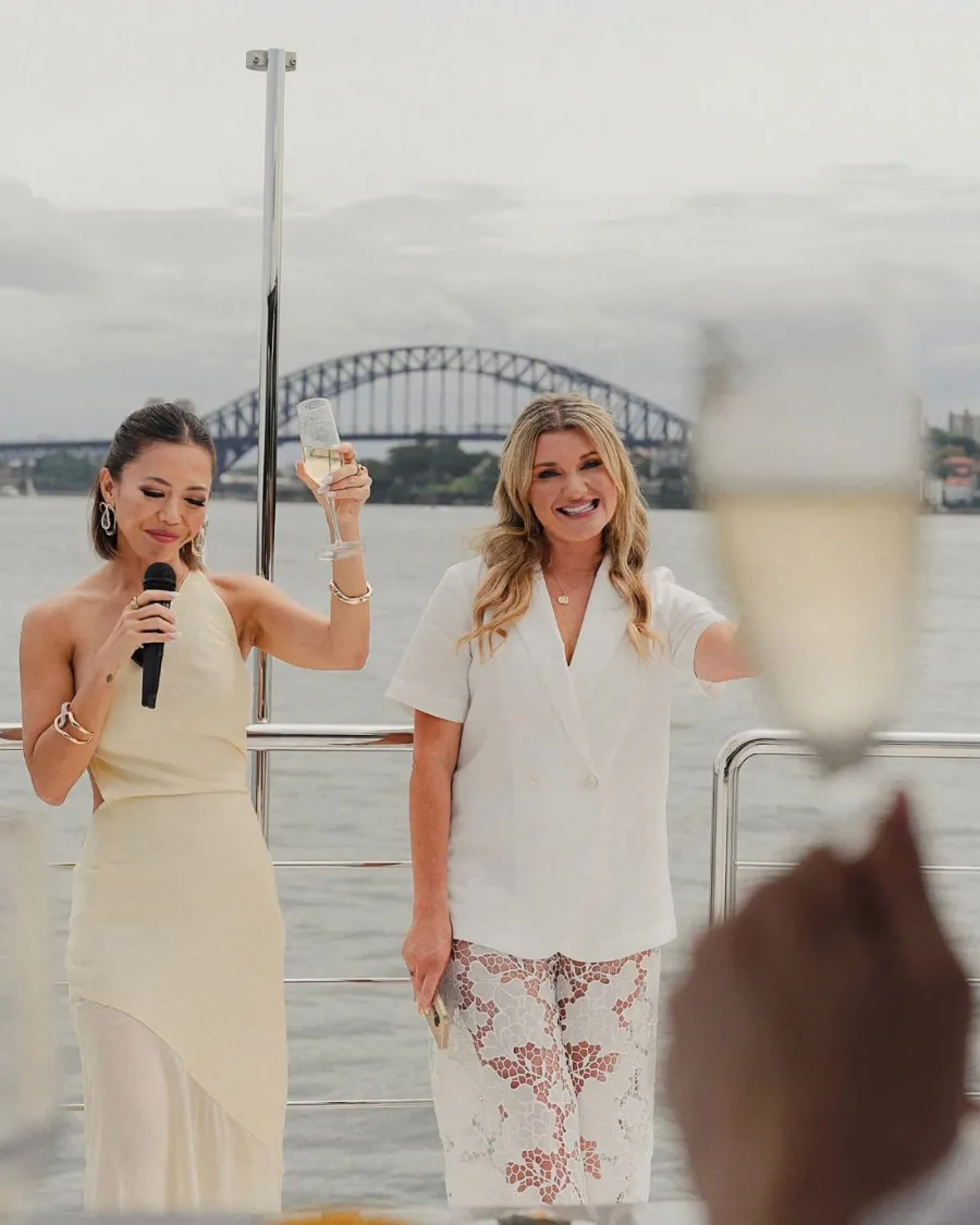 A host speaking to guests on deck with the Sydney Harbour Bridge behind